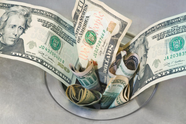 Money down the Drain. Cash dollars slipping down a drain.